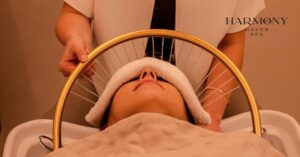 Head Spa procedúra v salónu Harmony Haven Ostrava – klientka relaxuje s přiloženým ručníkem na obličeji, zatímco terapeutka provádí masáž vlasové pokožky pomocí speciálního zařízení.